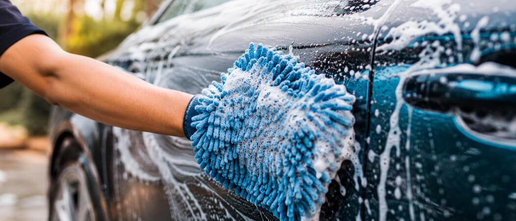safe car washing in the shade with microfiber mitt and car shampoo