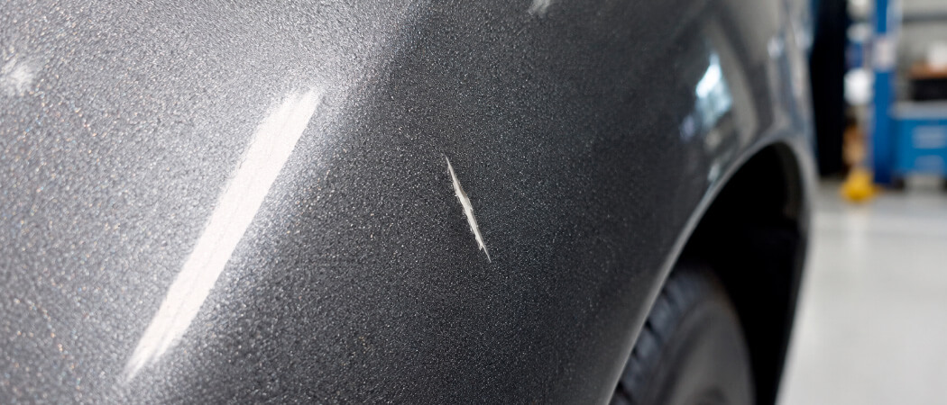 deep car scratch exposing the grey primer coat requiring paint repair