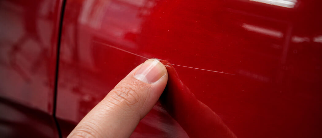 performing a fingernail test on a car paint scratch